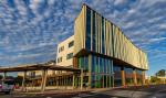 Modern office building with blue vertical fins and wooden canopy