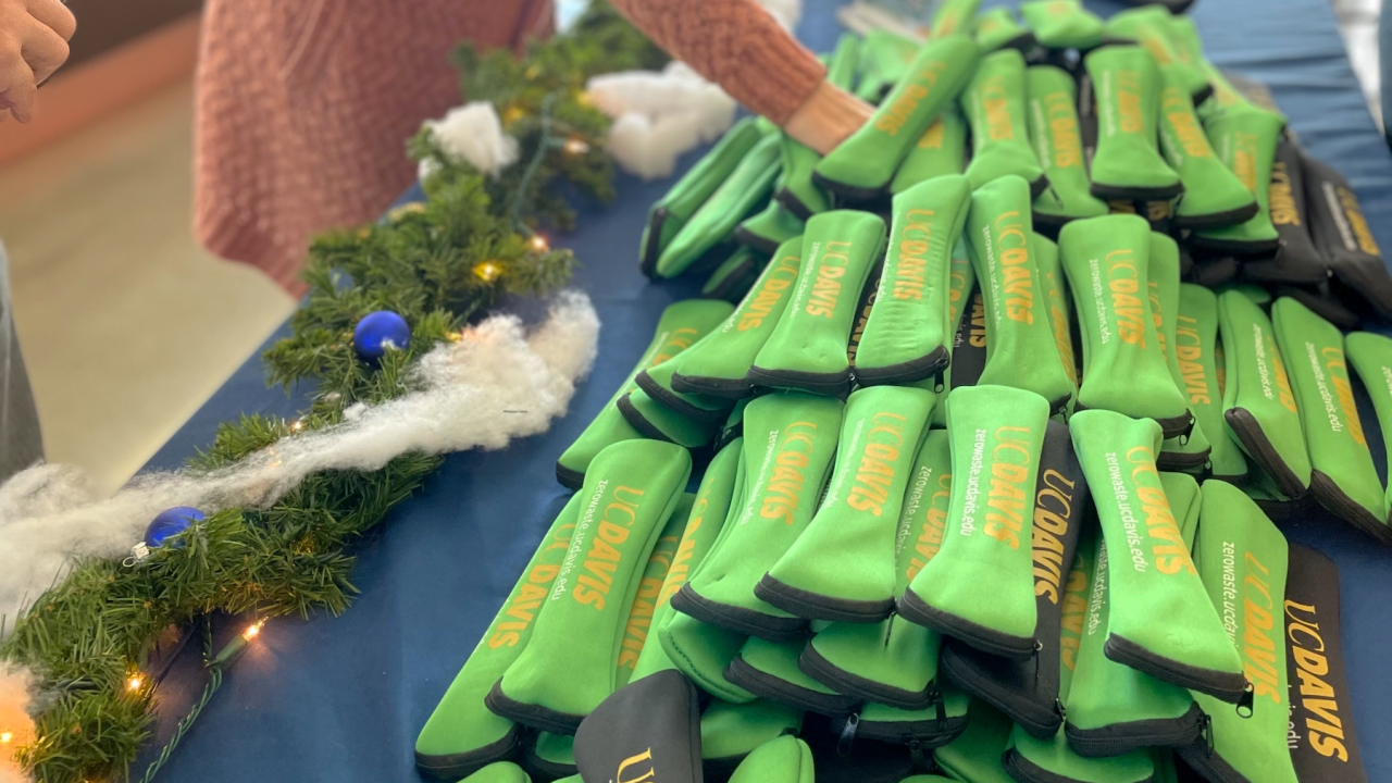 Person reaches for a reusable utensil kit, piled on a table