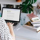 Image of a person filling out the UC Davis Sustainability Culture Survey on a laptop at a desk with their back to the camera.